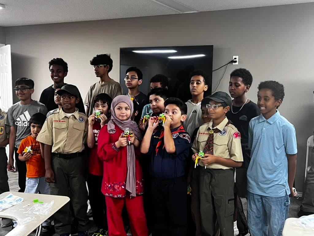 Scouts hold up the scribble bots they built, with team members standing behind them