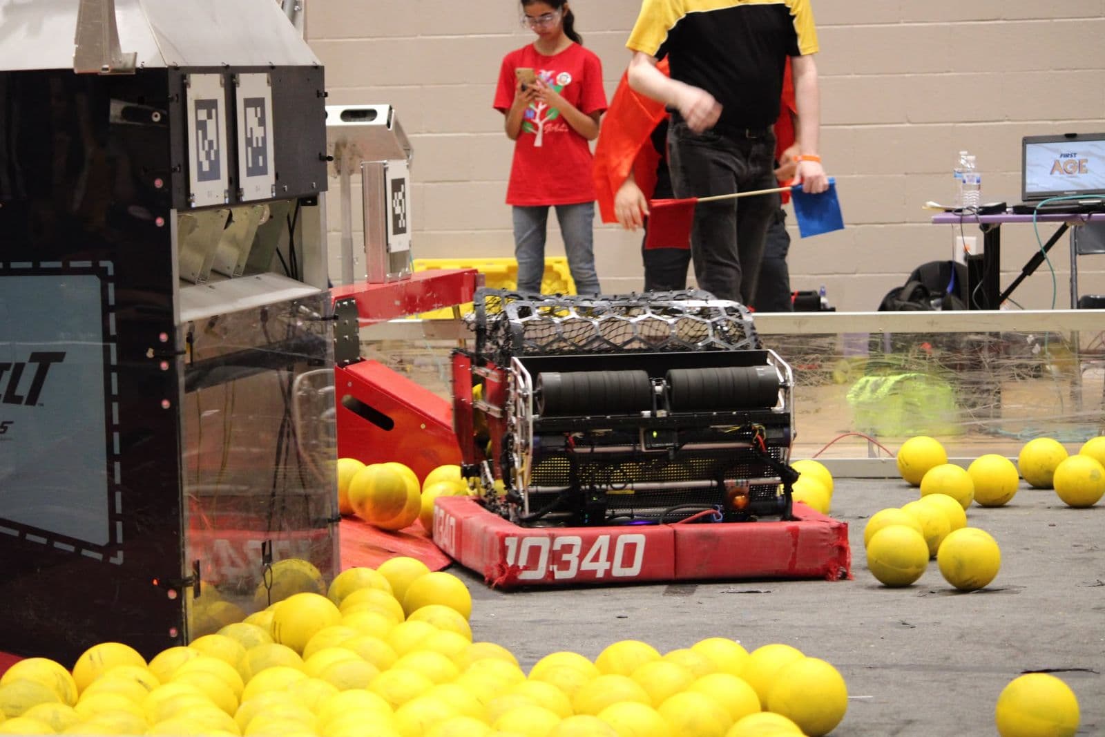 The 10340 robot in red bumpers at the field's goal, surrounded by yellow game pieces