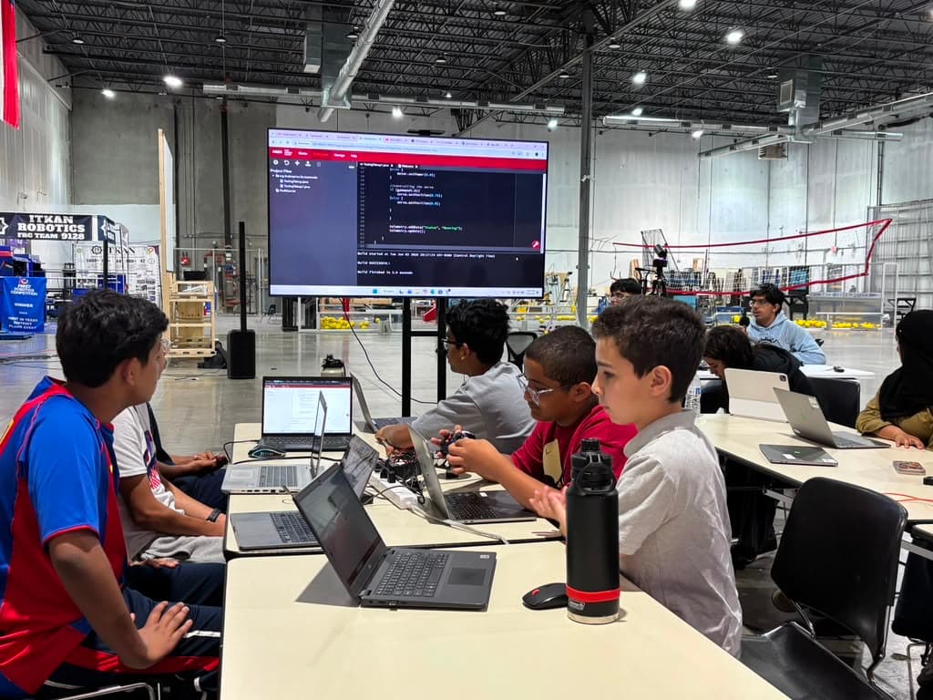 ITKAN students coding at laptops during Summer Training, FRC program on the big screen